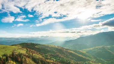 Dağların tepesinde bulutlarla mavi gökyüzünün zaman atlaması