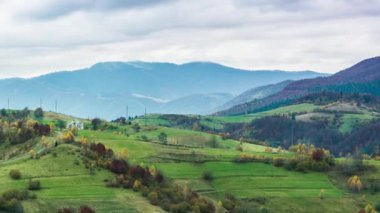 Beyaz ve kabarık bulutların altında yeşil tepelerin manzarası