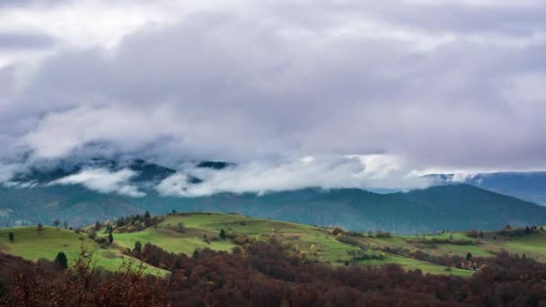 Landschappen van groene heuvels onder een laag witte en pluizige wolken — Stockvideo