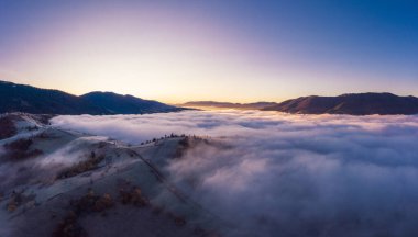 Gri sisle kaplı dağların tepesinde gün doğumu. Hava panoramik İHA görüntüsü