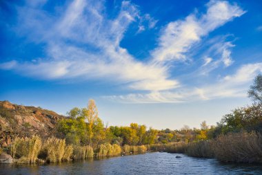 Ukrayna 'daki sıcak akşam ışığında küçük kuru bitkilerle kaplı büyük taşların arasında akan bir dere. Hava aracı görüntüsü