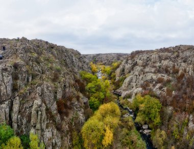 Aktovsky Kanyonu, Ukrayna 'da bir dere akar. Etrafta sonbahar ağaçları ve büyük taş kayalar var. Hava panoramik İHA görüntüsü