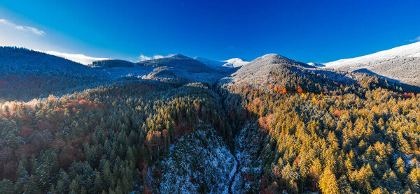 Picturesque mountain landscapes of autumn with snow near the village of Dzembronya in Ukraine Carpathians mountains.