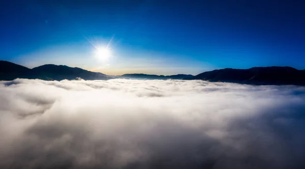 Sunrise over mountain hils covered with gray mist. Aerial panoramic drone shot