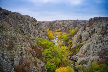 Aktovsky Kanyonu, Ukrayna 'da bir dere akar. Etrafta sonbahar ağaçları ve büyük taş kayalar var. Hava panoramik İHA görüntüsü