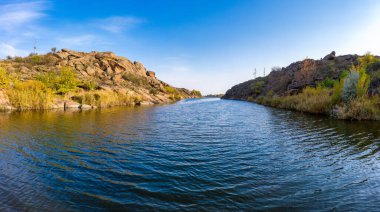 Ukrayna 'daki sıcak akşam ışığında küçük kuru bitkilerle kaplı büyük taşların arasında akan bir dere. Hava aracı görüntüsü