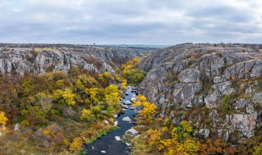 Aktovsky Kanyonu, Ukrayna 'da bir dere akar. Etrafta sonbahar ağaçları ve büyük taş kayalar var. Hava panoramik İHA görüntüsü