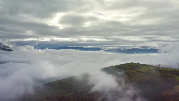 Survolez des paysages de collines verdoyantes sous une couche de nuages blancs et duveteux — Video