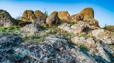 Resimli Ukrayna 'da sıcak güneşle dolu bir çayırda bitki örtüsüyle kaplı eski taş mineralleri ve onun güzel doğası.