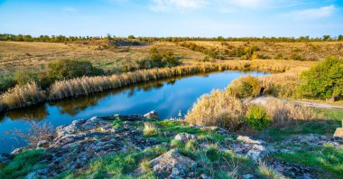 Büyük beyaz taşlar ve Ukrayna 'nın tepelerindeki yeşil bitki örtüsünün arasında parıldayan güzel bir nehir.