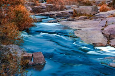 Ukrayna 'nın pitoresk doğası üzerine serin bir sonbaharda, sararmış altın otlarla kaplı beyaz ıslak taşların arasında fantastik bir dere akıyor.