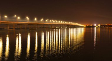 Uzun bir köprünün altından geçen Dinyeper nehrinin soğuk ışığında parlak fenerlerin güzel parlak yansıması.