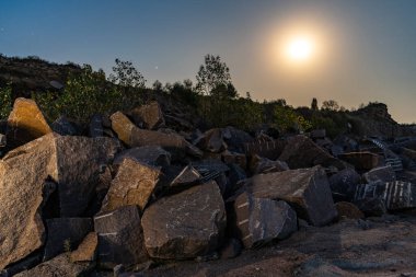 Karpatlar 'da bir maden ocağının yakınında büyük taş birikintileri parlak bir ay ile güzel bir gece gökyüzünün zeminine karşı.