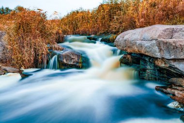 Ukrayna 'nın pitoresk doğası üzerine serin bir sonbaharda, sararmış altın otlarla kaplı beyaz ıslak taşların arasında fantastik bir dere akıyor.