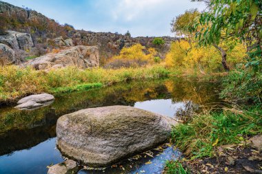 Hızlı, sığ ve temiz bir dere, Ukrayna 'da rüzgarda savrulan uzun kuru topaklarla çevrili yumuşak ve büyük taşların arasında akar.
