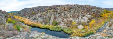 Resimli Ukrayna 'daki küçük bir nehrin üzerinde yeşil bitki örtüsüyle kaplı çok sayıda taş minerali ve onun güzel doğası.