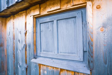 Alışılmadık şekilleri olan eski bir evin güzel ahşap duvarında çok küçük kapalı bir pencere.