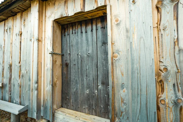 一间有不寻常图案的老房子的漂亮木墙中的小闭锁的门 — 图库照片