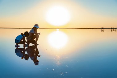 Güzel, şeffaf bir gölde iki kız parlak bir yüzey arıyor.