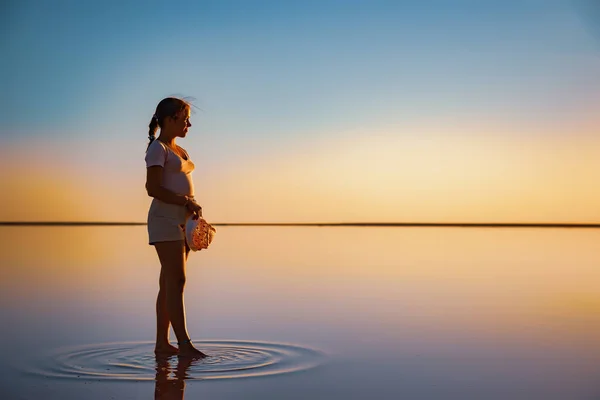 Menina feliz caminha ao longo do lago espelho apreciando as vistas do sol da noite do pôr do sol ardente — Fotografia de Stock