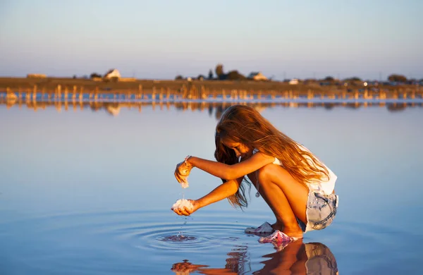 A little girl is looking at salt in a transparent water surface on a transparent background — Stock Photo, Image