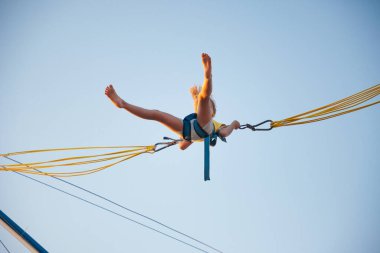 Küçük kız lastik bantlarla uçar ve trambolinde zıplar.