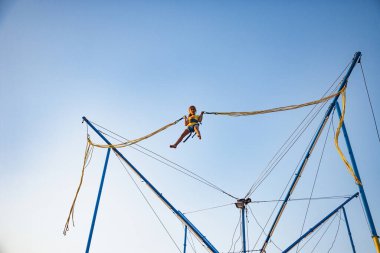 Küçük kız lastik bantlarla uçar ve trambolinde zıplar.