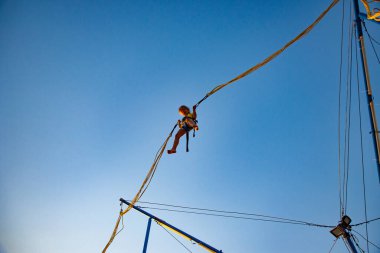 Küçük kız lastik bantlarla uçar ve trambolinde zıplar.