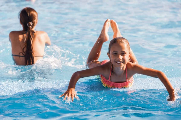 Chica alegre jugando en una piscina y mirando sonriendo a la cámara — Foto de Stock