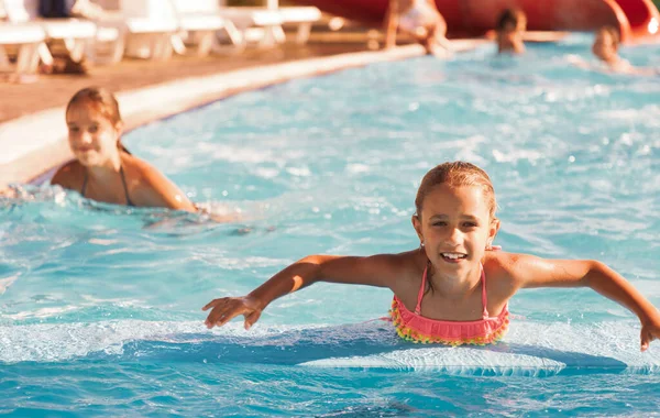 Chica alegre jugando en una piscina y mirando sonriendo a la cámara — Foto de Stock