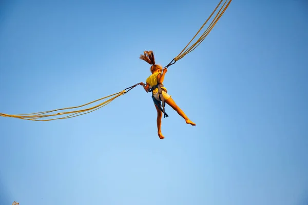 Маленькая девочка летает на упругих лентах и прыгает на батуте — стоковое фото