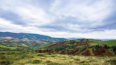 Beyaz ve kabarık bulutların altında yeşil tepelerin manzarası