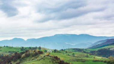 Beyaz ve kabarık bulutların altında yeşil tepelerin manzarası