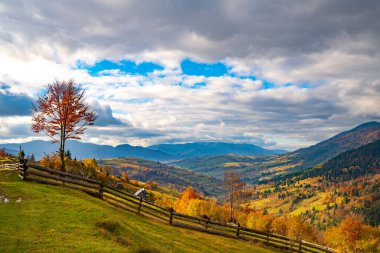 Muhteşem tepelerin altında küçük bir köy. Sonbahar renkli ormanlarla kaplı. Parlak, sıcak bir güneş ışığı altında.