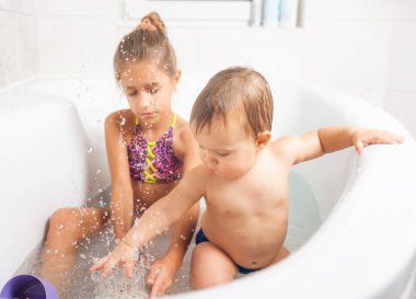 Kız, erkek kardeşiyle tuvalette oynuyor.