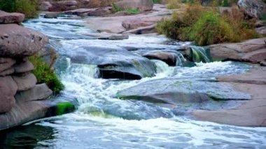 Pürüzsüz ve karanlık taşların arasında küçük parlak bir dere akıyor.