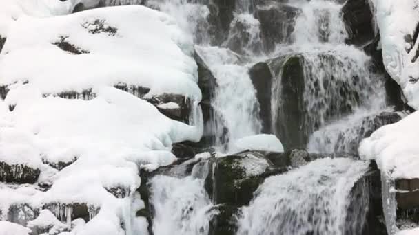 De petits ruisseaux d'eau froide coulent parmi les pierres recouvertes de neige — Video