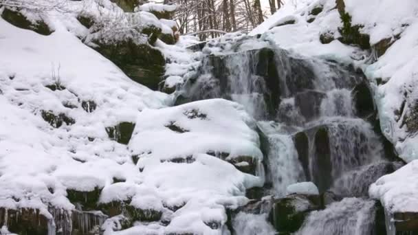 Kis patakok hideg víz áramlik a kövek között hóval borított — Stock videók