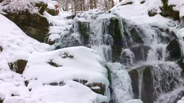 Små strömmar av kallt vatten rinner bland stenarna täckta med snö — Stockvideo