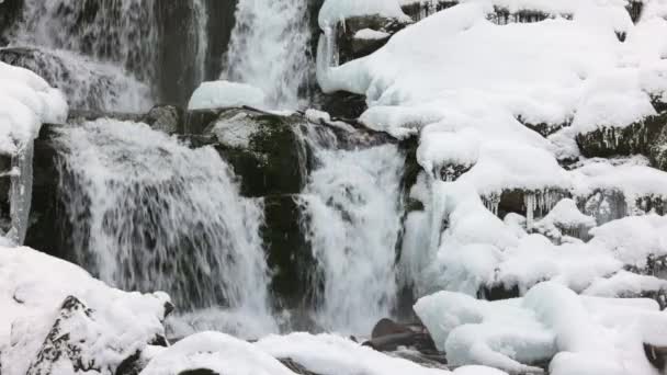Små strömmar av kallt vatten rinner bland stenarna täckta med snö — Stockvideo