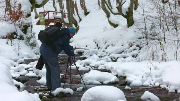En man använder en kamera för att fånga en bergsbäck i Karpaterna. — Stockvideo