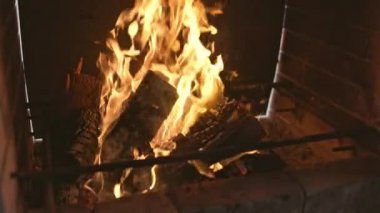 Parlak bir şenlik ateşi, kararmış odunları ve barbekü duvarlarını yakar.