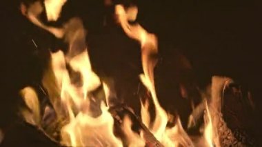 Parlak bir şenlik ateşi, kararmış odunları ve barbekü duvarlarını yakar.