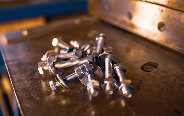 Metal chrome bolts and nuts lie on the shiny metal surface of the machine — Stock Photo, Image
