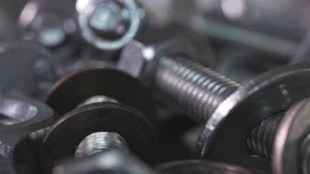 Slider shot video of chrome bolts and nuts in a chaotic order industrial background — Stock Video