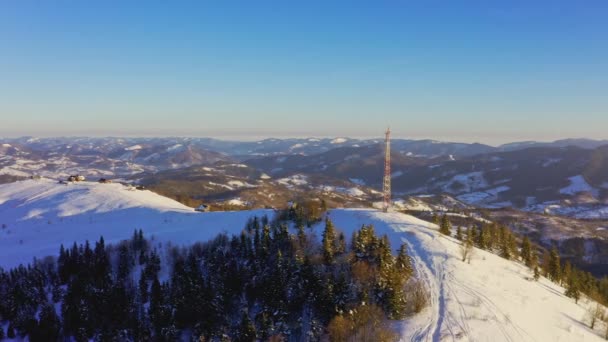 Πετώντας πάνω από πύργο ραδιοεπικοινωνιών, χιόνι βουνό καλύπτονται χειμερινό τοπίο. — Αρχείο Βίντεο