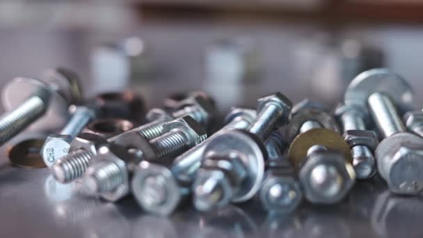 Slider shot video of chrome bolts and nuts in a chaotic order industrial background — Stock Video