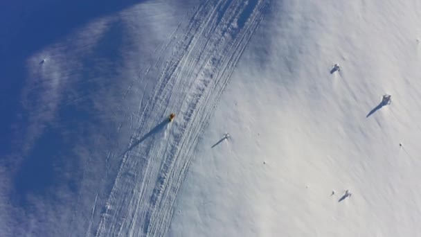 Een snelle man op een sneeuwscooter rijdt een verlaten helling van een besneeuwde berg bij een heldere zonsondergang — Stockvideo