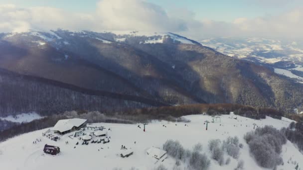 Παλιό σταθμό σκι σε μια χιονισμένη πλαγιά βουνού με πολύ κόσμο σε σκι και snowboards — Αρχείο Βίντεο