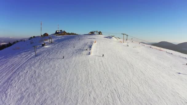 Gammel skistasjon på en snødekt fjellskråning med mange mennesker på ski og snowboard – stockvideo